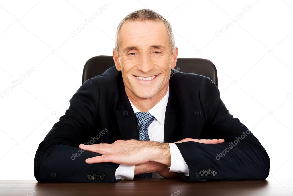 Happy businessman sitting at his desk