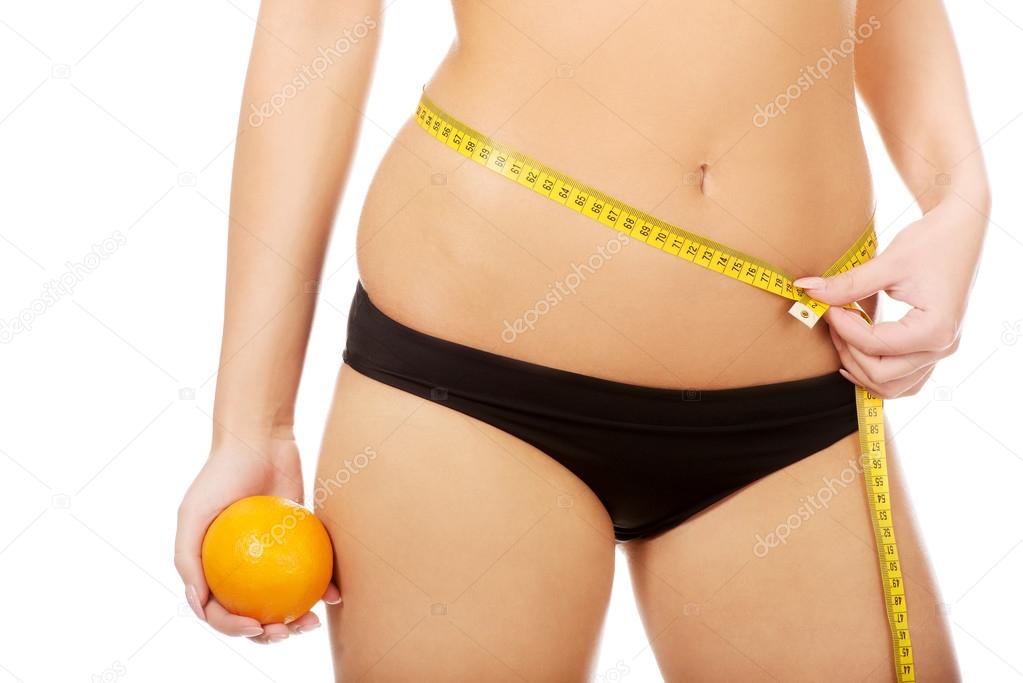 Woman with apple measuring her waist.