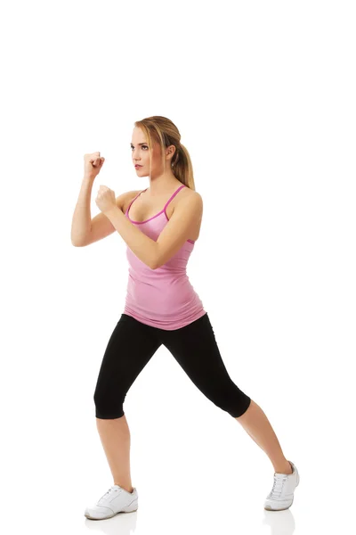 Jovem mulher em pose de fitness pontapé . — Fotografia de Stock