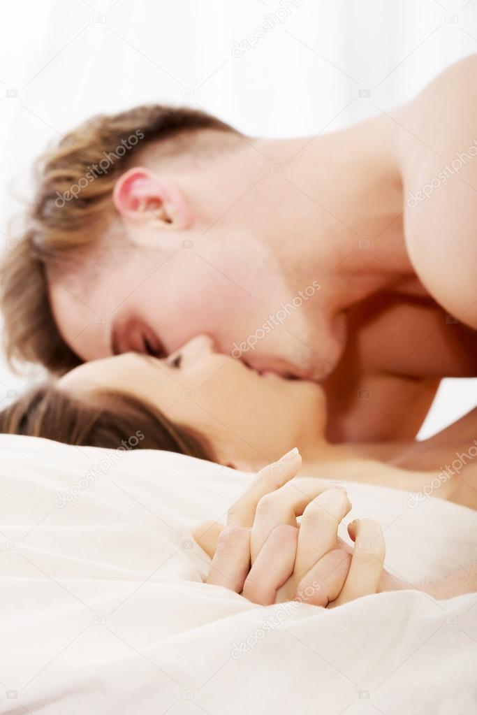 Couple kissing on bed.