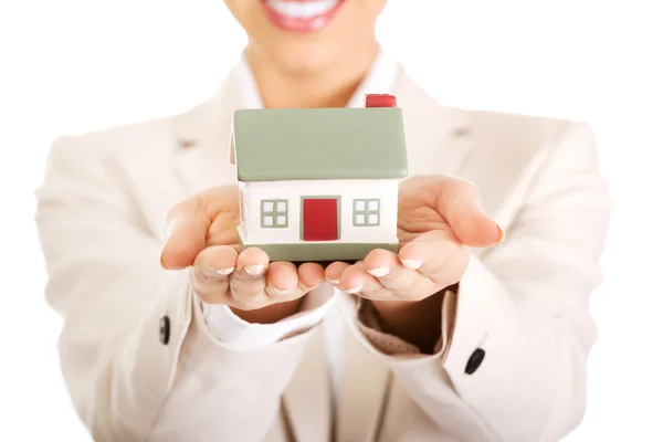 Businesswoman holding small house on palm. — Stock Photo, Image