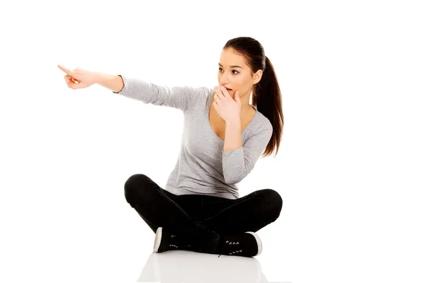 Vrouw zitten cross legged wijzen opzij. — Stockfoto