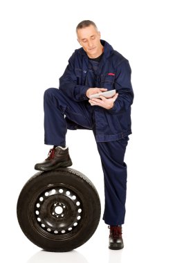 Lastik ve tabletle gülümseyen tamirci.