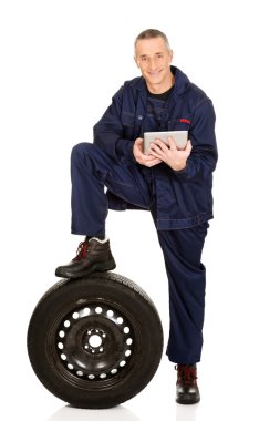 Lastik ve tabletle gülümseyen tamirci.