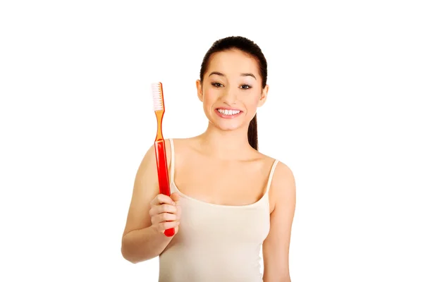 Mujer joven sosteniendo un cepillo de dientes grande . — Foto de Stock