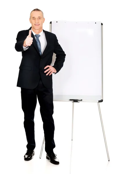 Homme exécutif avec ok signe près de flip chart — Photo
