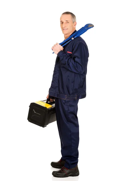 Зрелый рабочий с сумкой для инструментов и гаечным ключом — стоковое фото