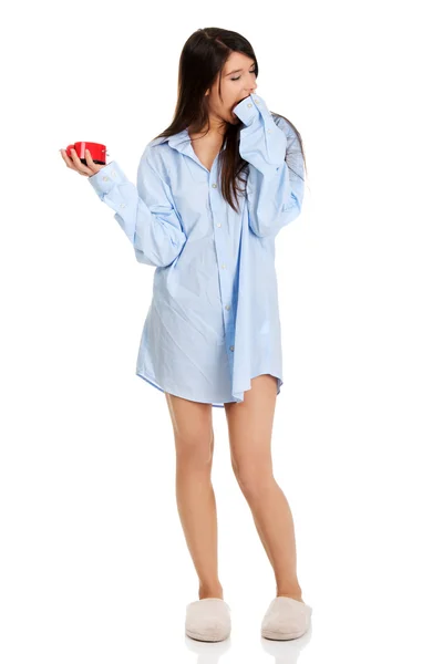 Mujer joven con camisa grande sosteniendo el despertador . — Foto de Stock