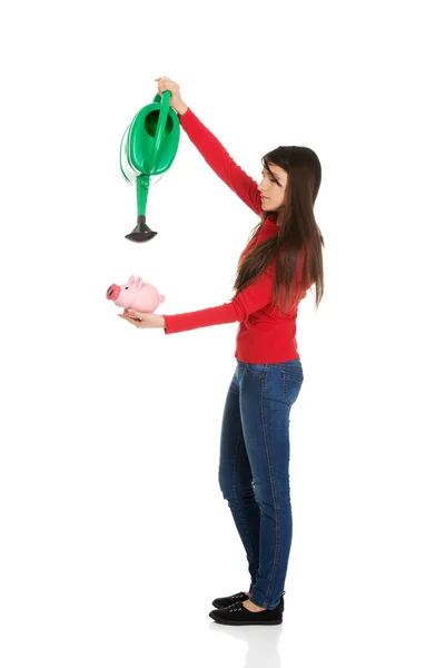 Woman watering piggybank. — Stock Photo, Image