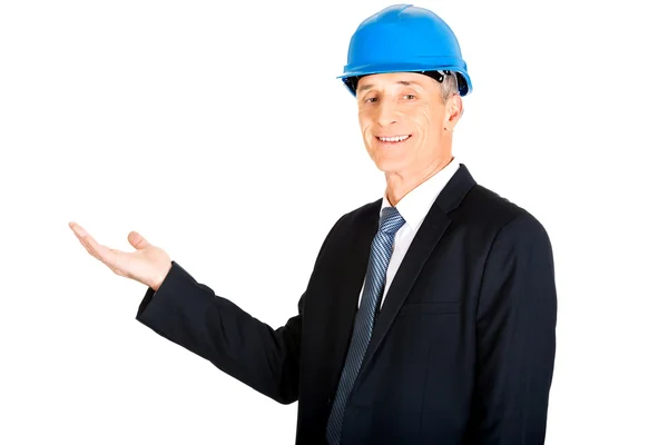 Businessman in hard hat presenting something — Stock Photo, Image