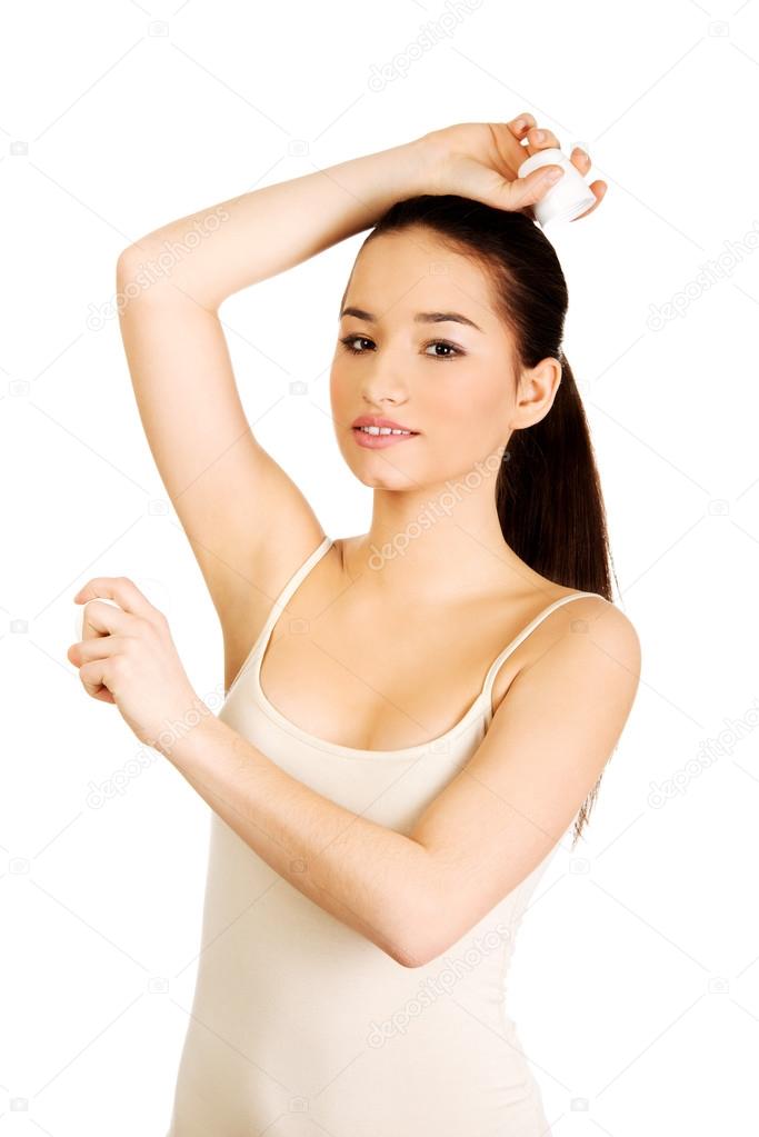 Young woman applying anti perspirant.