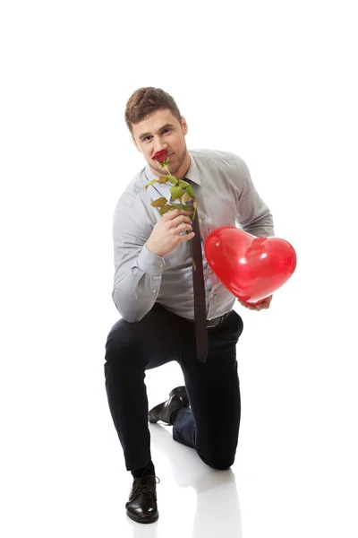 Hombre arrodillado con rosa roja y globo del corazón . — Foto de Stock