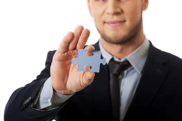 Pohledný podnikatel drží kus puzzle. — Stock fotografie