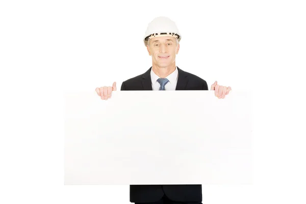 Empresario con sombrero duro sosteniendo banner vacío — Foto de Stock