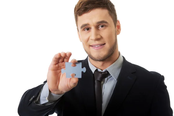 Hombre de negocios guapo sosteniendo la pieza del rompecabezas . — Foto de Stock