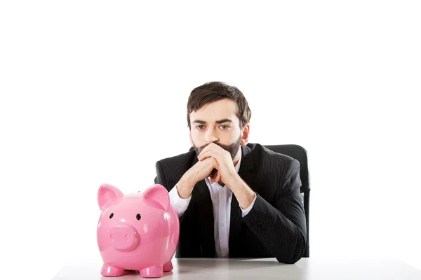 Affärsman med piggybank av ett skrivbord. — Stockfoto