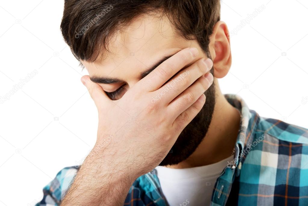 Depressed man touching his face.