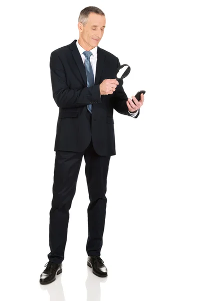 Biznesmen z lupą i telefon komórkowy — Zdjęcie stockowe