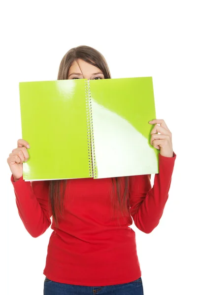 Woman hiding her face behind a notebook. — Stock Photo, Image