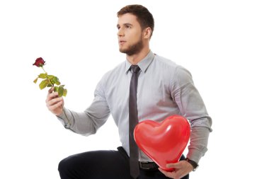 Rose ve balon ile diz çökmüş adam.