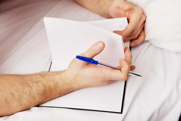 Чоловік пише записку в ліжку . — стокове фото