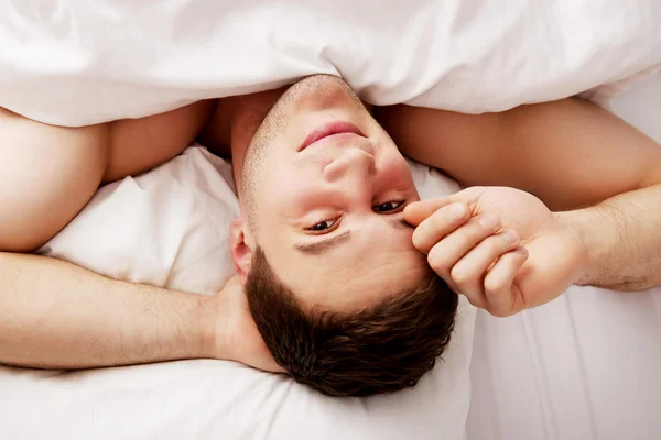 Schöner junger Mann liegt im Bett. — Stockfoto