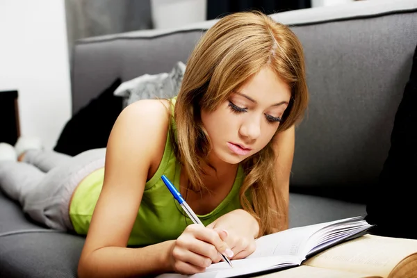 Kobieta uczenia się do egzaminu na kanapie. — Zdjęcie stockowe