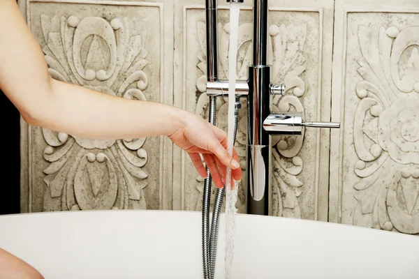 Frau gießt Wasser in Badewanne. — Stockfoto