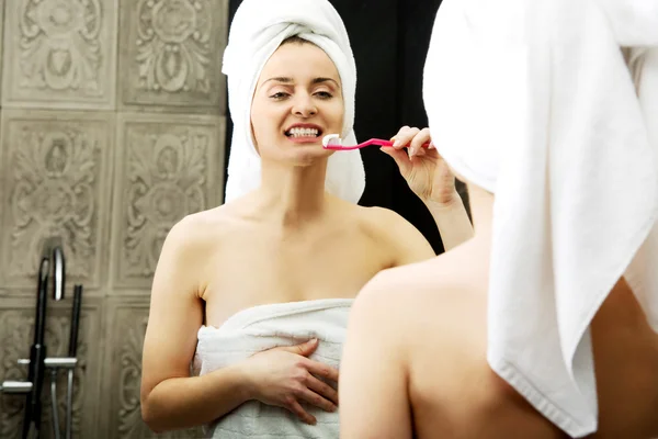 Mujer cepillarse los dientes en el baño. —  Fotos de Stock