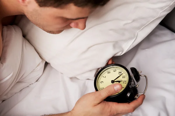 Mann mit Wecker im Schlafzimmer. — Stockfoto