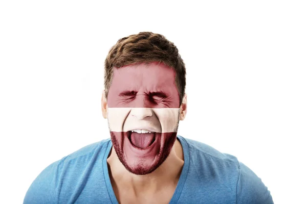 Screaming man with Latvian flag on face. — Stock Photo, Image