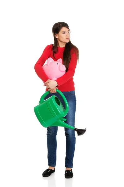 Woman with a watering can and piggybank. — Stock Photo, Image