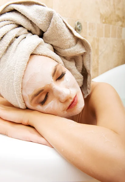 Frau entspannt sich im Badezimmer mit Gesichtsmaske. — Stockfoto