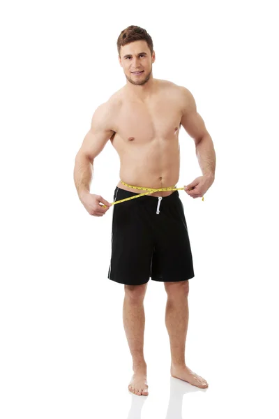 Muscular man measuring his belly. — Stock Photo, Image