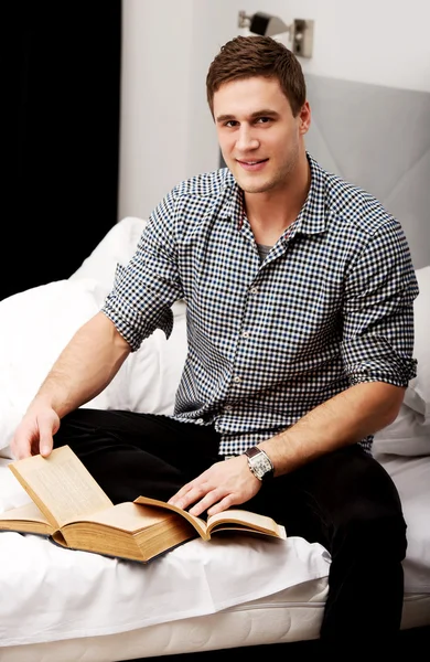 Un hombre con un libro en su cama . — Foto de Stock