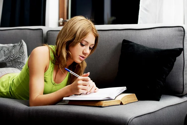 Jeune femme apprenant à examiner sur un canapé . — Photo