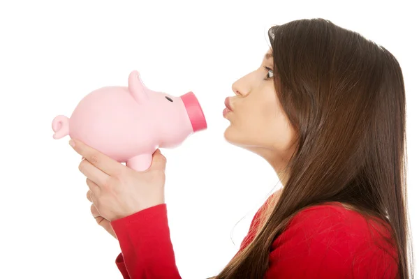 Ung kvinna kysser en piggybank. — Stockfoto