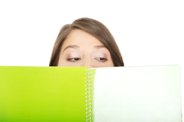 Mujer escondiendo su cara detrás de un cuaderno . — Foto de Stock