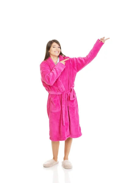 Woman in pink bathrobe pointing aside. — Stock Photo, Image