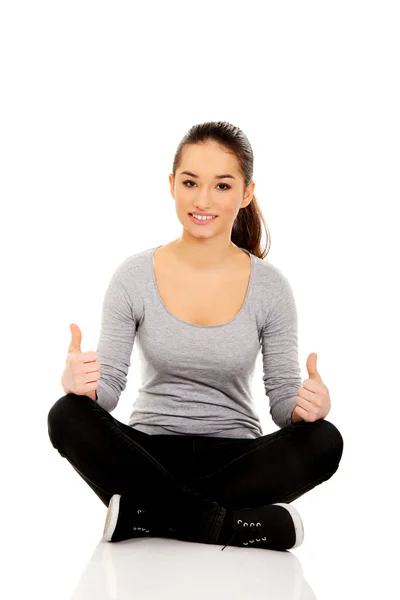 Woman sitting cross legged with thumbs up. — Stock Photo, Image
