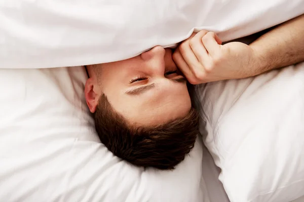 Man rubs his eyes on the bed. — Stock Photo, Image