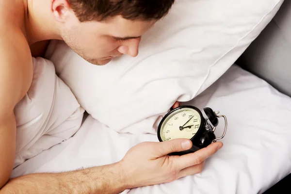 Man met wekker in slaapkamer. — Stockfoto