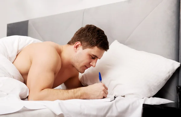 Man schrijven van een notitie in zijn bed. — Stockfoto