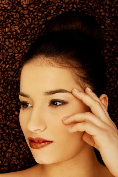 Attractive woman lying in coffee grains. — Stock Photo, Image