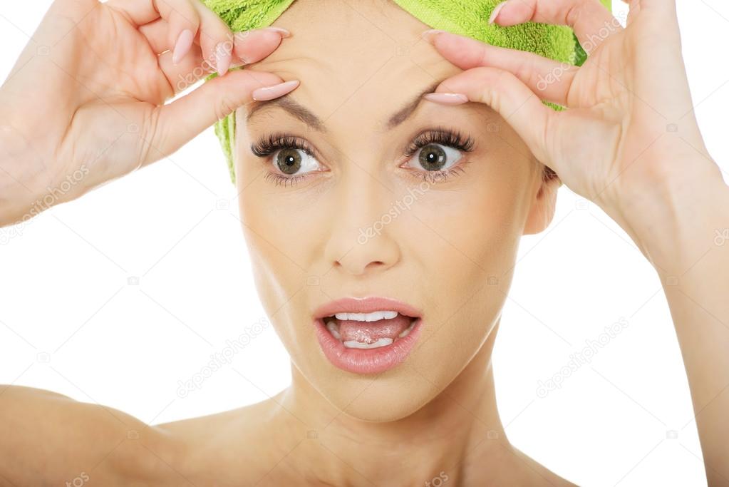 Woman checking wrinkles on her forehead.