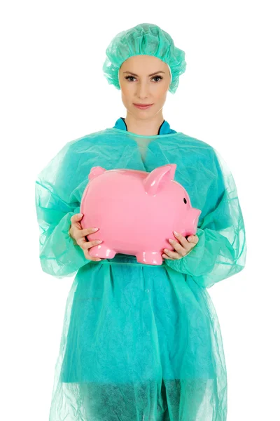 Vrouwelijke arts met roze piggy bank. — Stockfoto