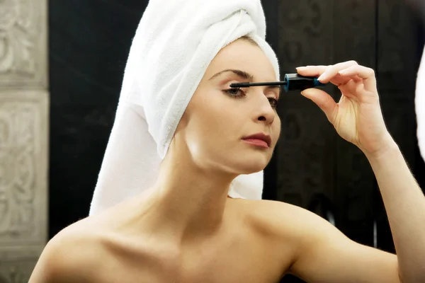 Donna che utilizza mascara nello specchio del bagno . — Foto Stock