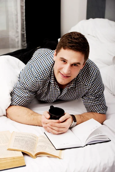 Glücklicher Mann mit einem Buch im Bett. — Stockfoto