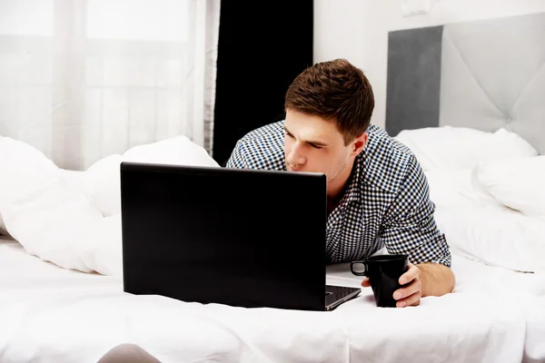 Przypadkowy człowiek korzysta z laptopa w łóżku — Zdjęcie stockowe