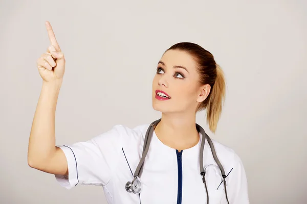 Jovem médica mulher apontando para cima . — Fotografia de Stock